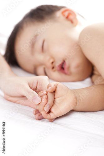 Mother holding sleeping baby's hand