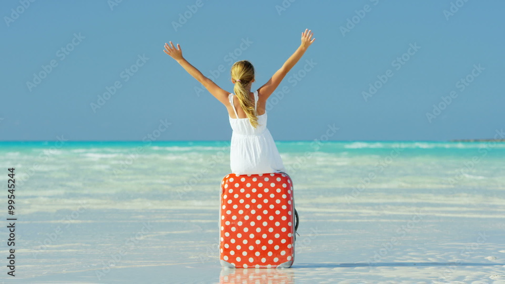 Blonde female Caucasian child on beach sitting on a suitcase Blonde female Caucasian child on beach sitting on a suitcase