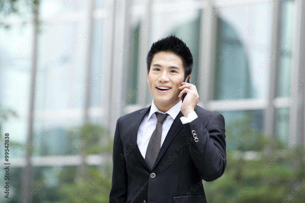 Young businessman on the phone outside a building, Hong Kong Young businessman on the phone outside a building, Hong Kong