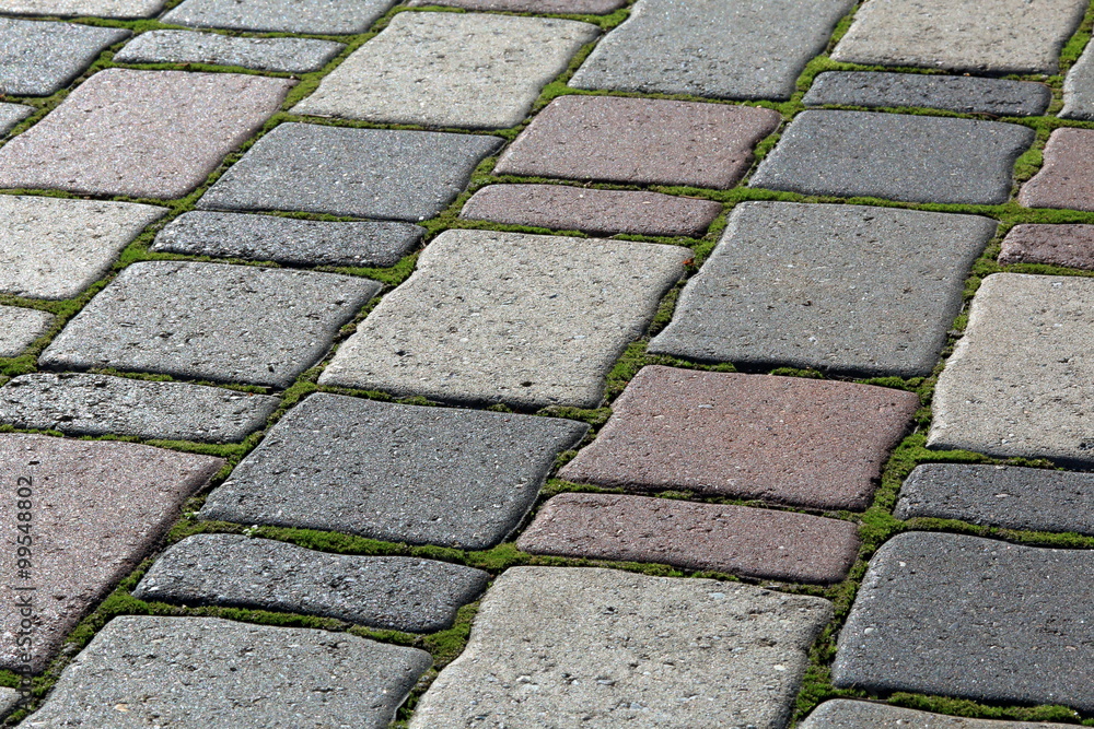 Old pavement from colored stones with growing the moss