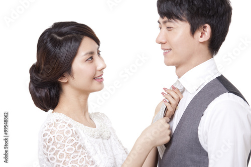 Young woman tying necktie for young man