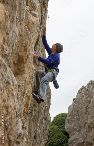 Young male climber hanging on a cliff with a rope.