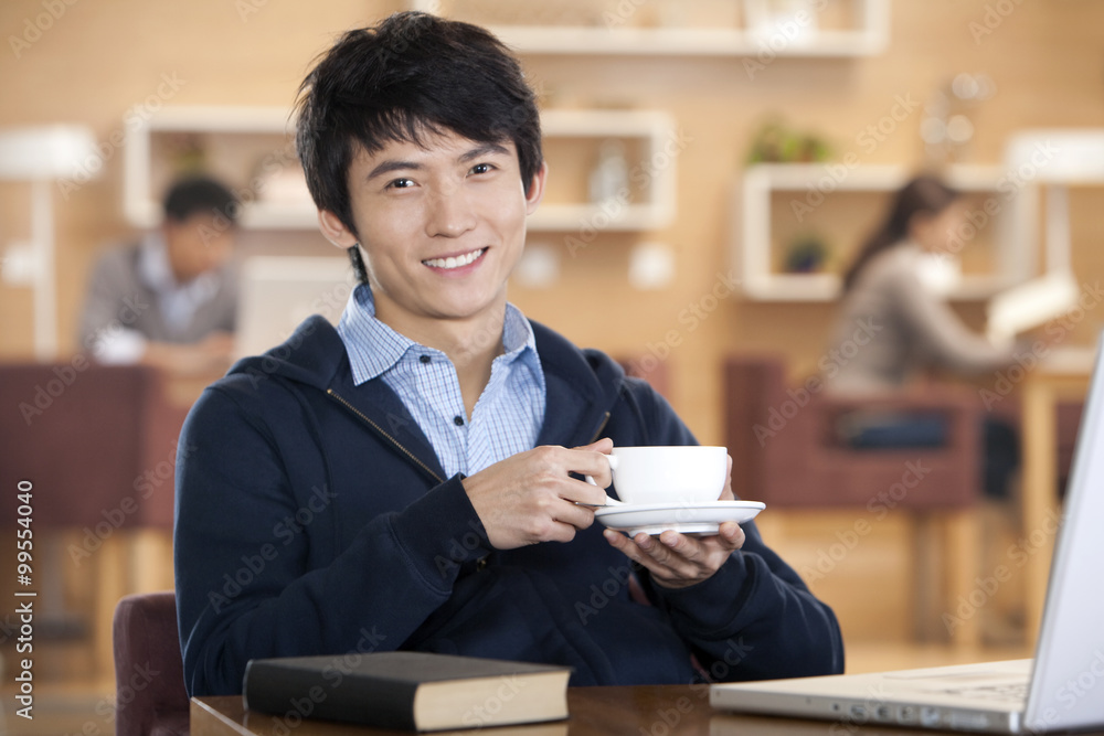 Young man holding coffee cup inside coffee shop Young man holding coffee cup inside coffee shop