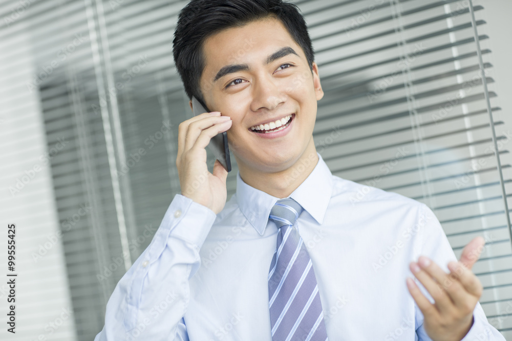 Young businessman talking on cell phone in office Young businessman talking on cell phone in office