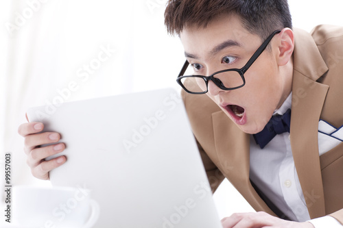 Fashionable businessman with laptop looking astonished