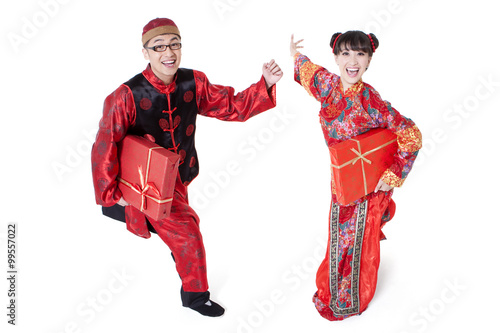 Excited young couple in traditional Chinese clothing running with gift boxes in hands