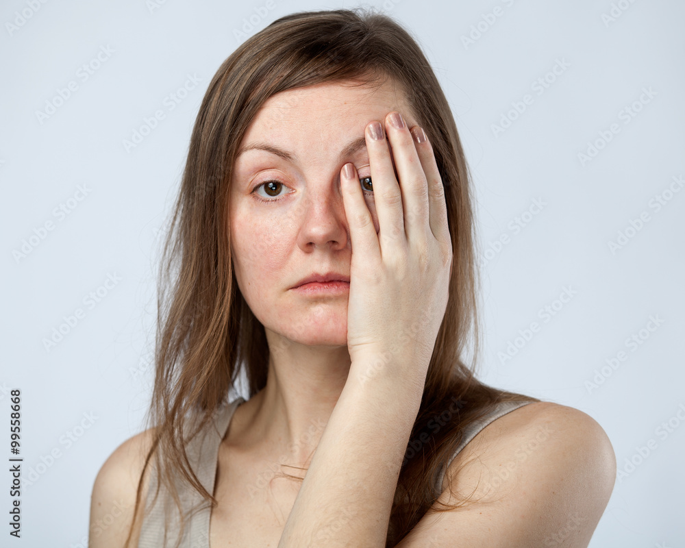 Portrait of a sad woman closing one eye Portrait of a sad woman closing one eye