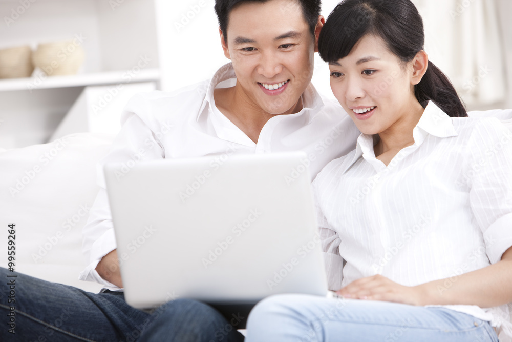 Young couple using laptop in sofa Young couple using laptop in sofa