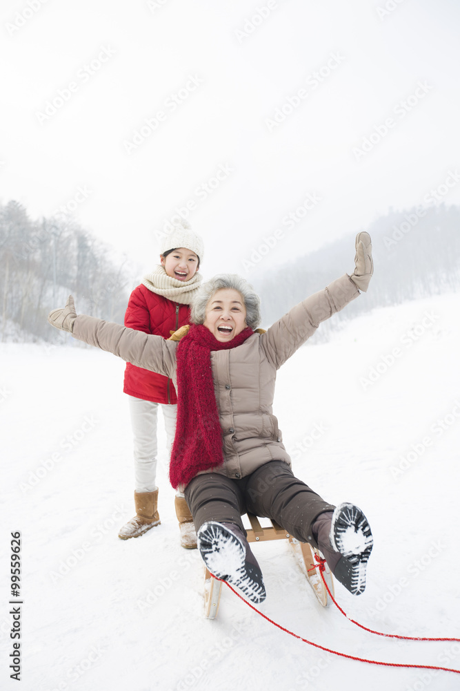 Granddaughter pushing grandmother on sled