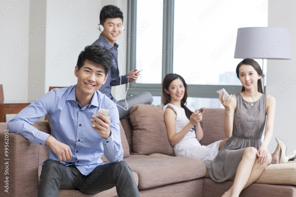 Young friends sitting on the sofa  with smart phones 