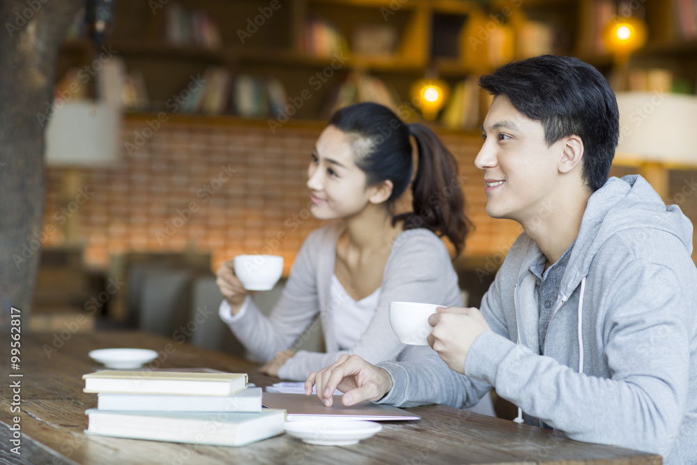 Young man and woman drinking coffee in cafe