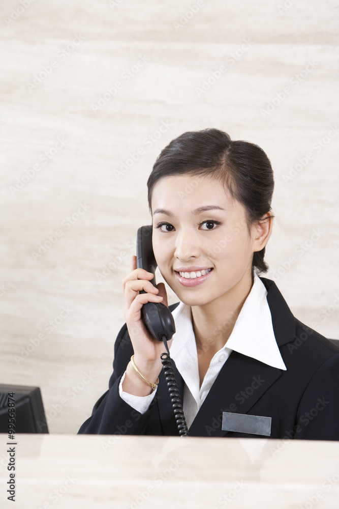 Young Receptionist On Telephone At Front Desk Young Receptionist On Telephone At Front Desk