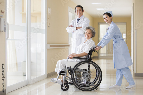 Medical workers taking care of senior woman in wheel chair