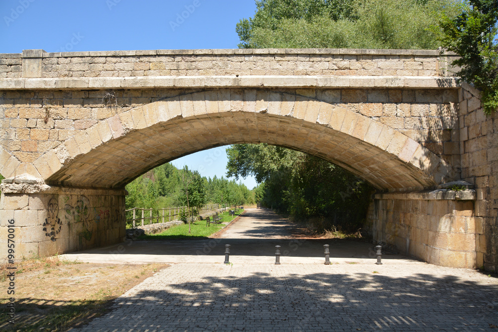 camino bajo un  puente de piedra