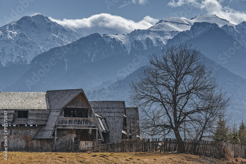 Rural scenery with old abandoned wooden farmhouse in the valley of snowy Bucegi mounains, Brasov county, Romania.