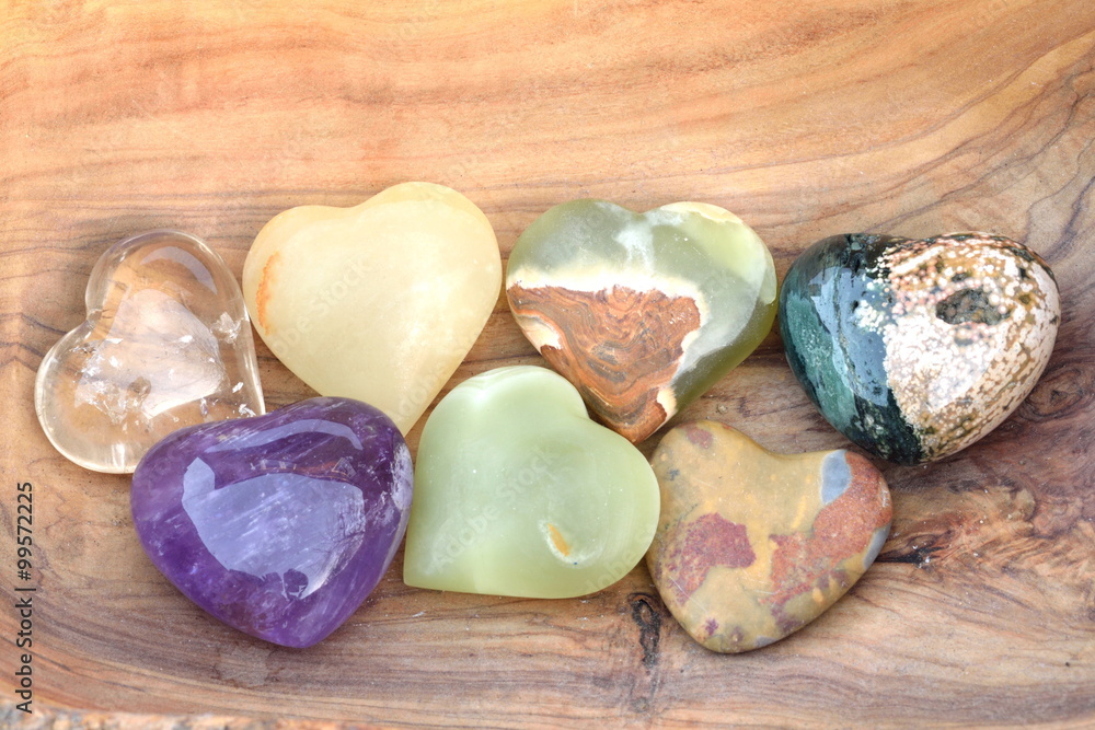 Group of heart shaped coloured stones on a wooden background Group of heart shaped coloured stones on a wooden background