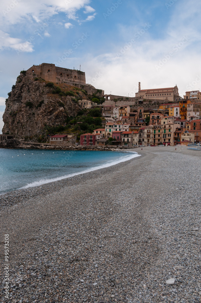 Stone beach and old small italian town on cliff under blue sky