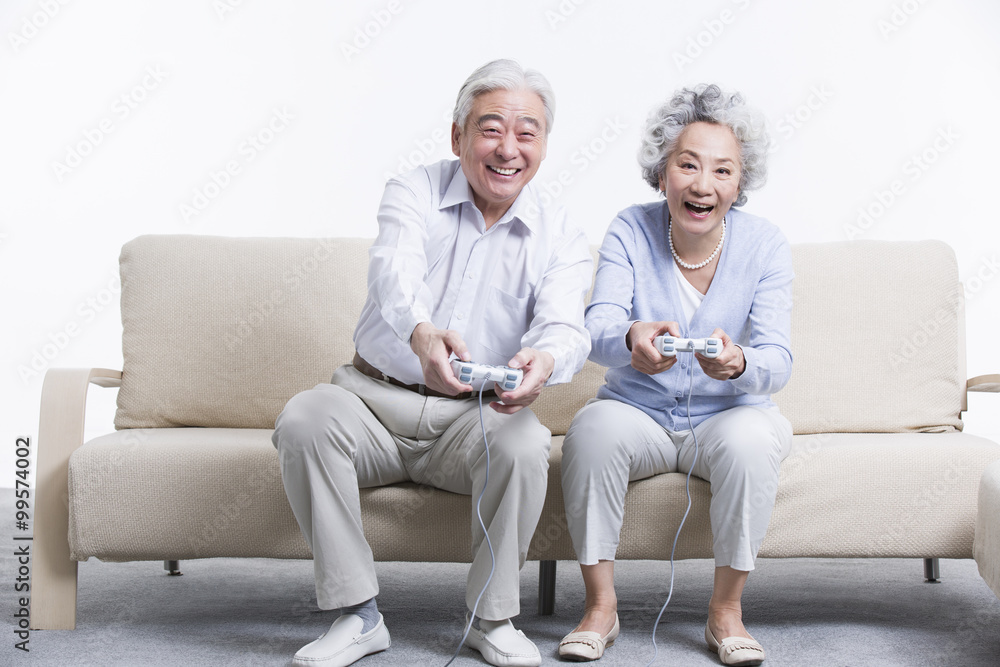 Senior couple playing video game in living room Senior couple playing video game in living room