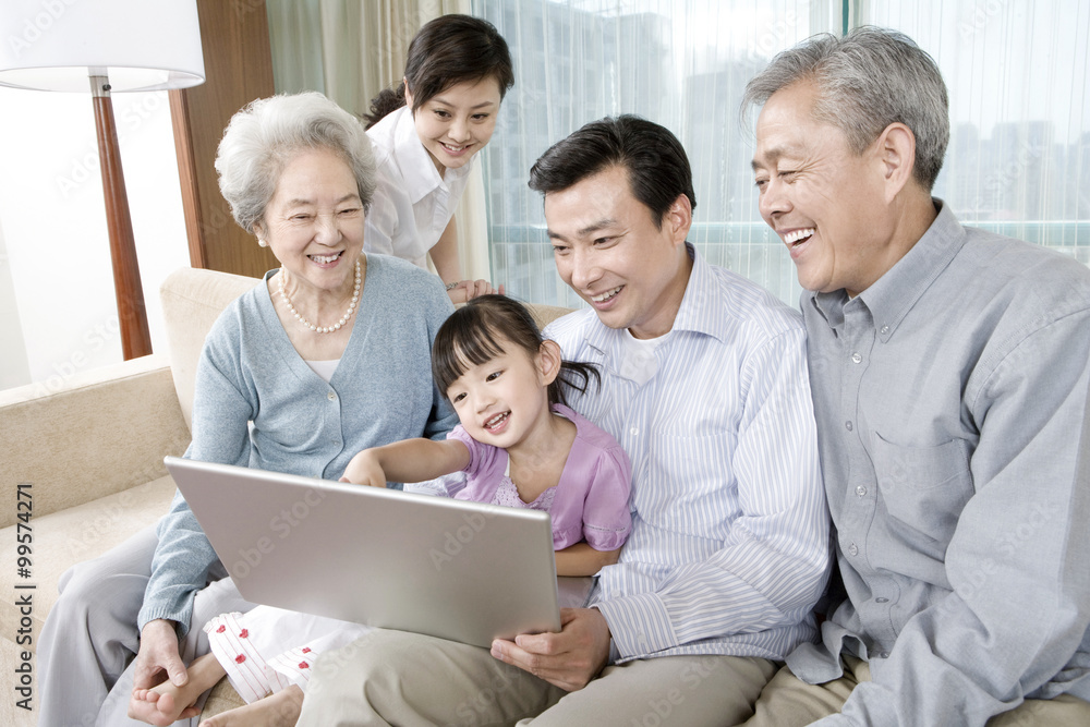 Grandparents and Parents with daughter look at Laptop on a sofa Grandparents and Parents with daughter look at Laptop on a sofa