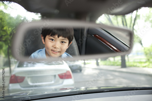 Fotografi Reflection of cute boy on car rearview mirror