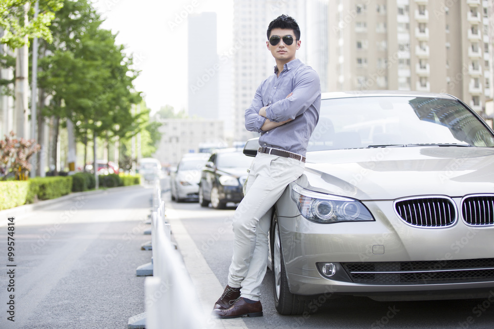 Naklejka premium Young man leaning against his car
