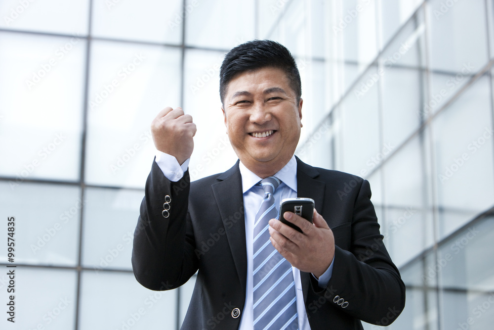 Happy businessman with mobile phone and raised fist Happy businessman with mobile phone and raised fist