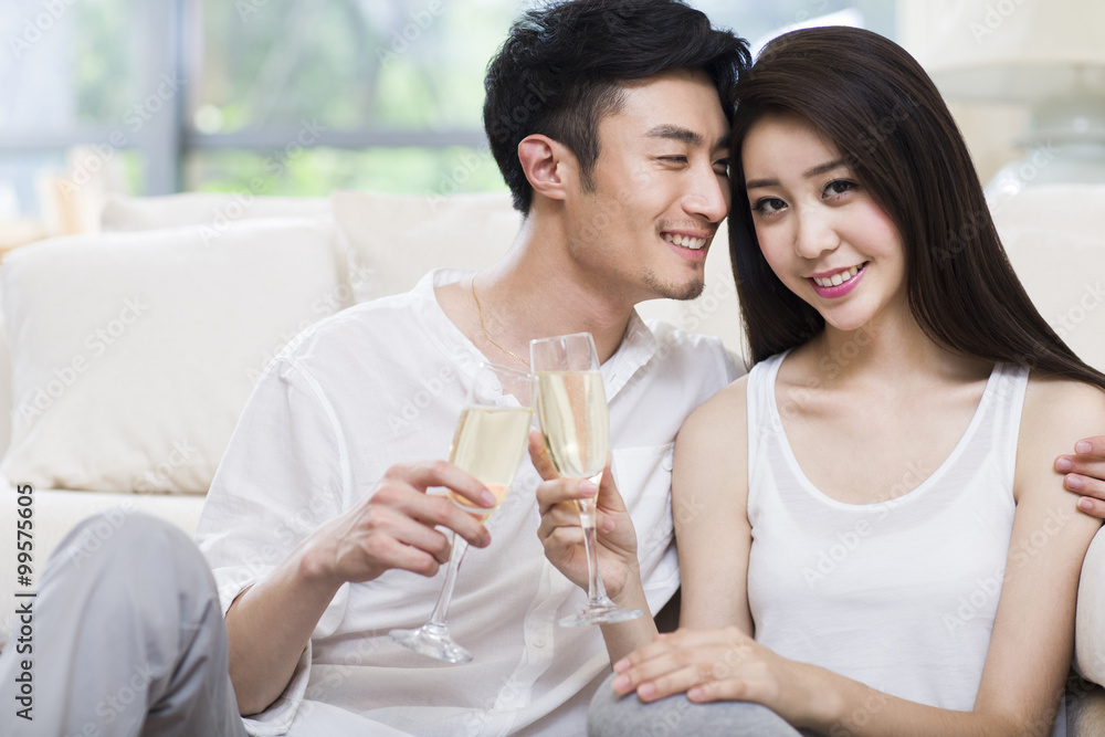 Cheerful young couple drinking champagne in living room Cheerful young couple drinking champagne in living room