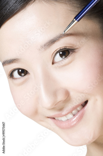 Beauty shot of a young woman penciling eyebrow