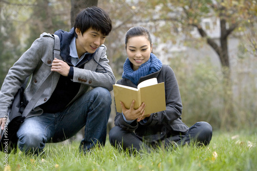 A young woman and man looking through a book together