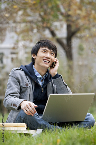 A young man talking on the phone and using computer