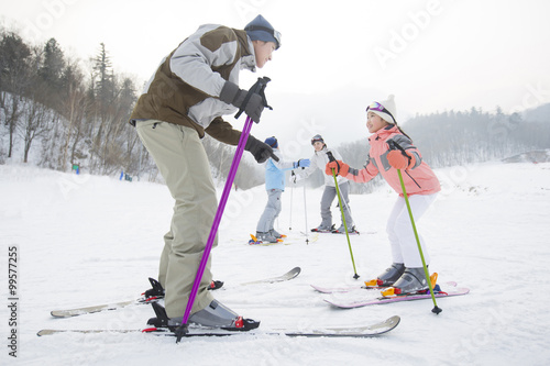 Young parents teaching children to ski