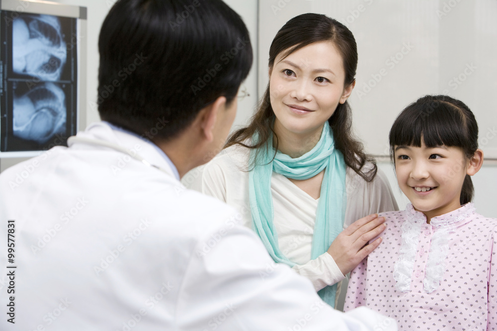 Doctor speaking with his young patient and her mother Doctor speaking with his young patient and her mother