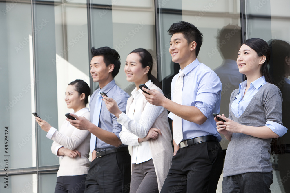 Businesspeople leaning on the wall with mobile phones