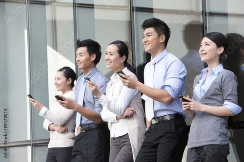 Businesspeople leaning on the wall with mobile phones