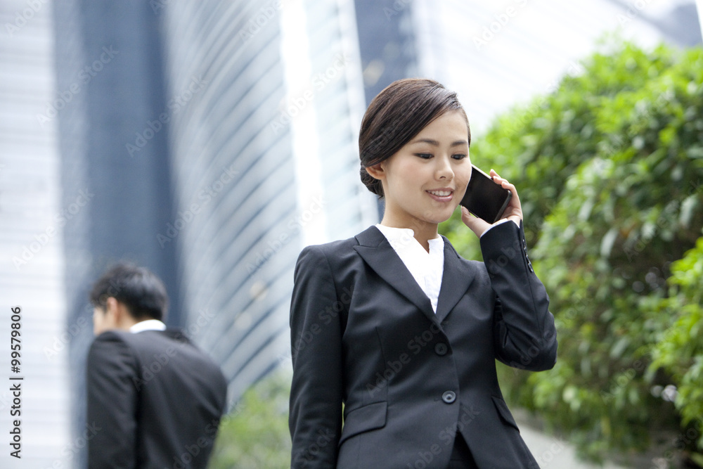 Happy business workers walking and talking on the phone outside a building, Hong Kong Happy business workers walking and talking on the phone outside a building, Hong Kong
