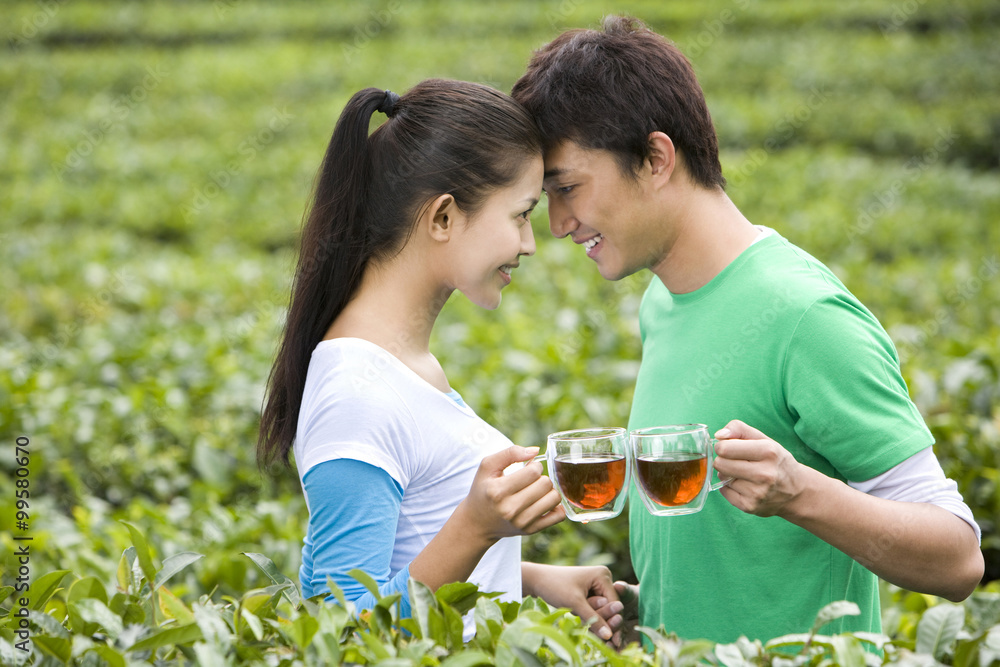 Young Couple in Tea Field with Freshly Brewed Tea Young Couple in Tea Field with Freshly Brewed Tea