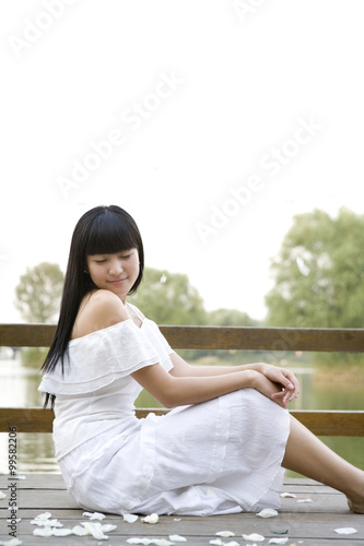 Young woman sitting by lake Free Download Young woman sitting by lake - GFXLoad