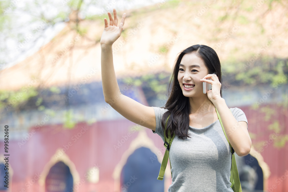 Young woman talking on the phone and waving Young woman talking on the phone and waving