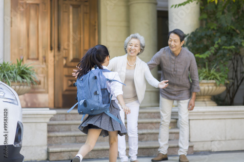 Schoolgirl running towards to her grandparents © Blue Jean Images