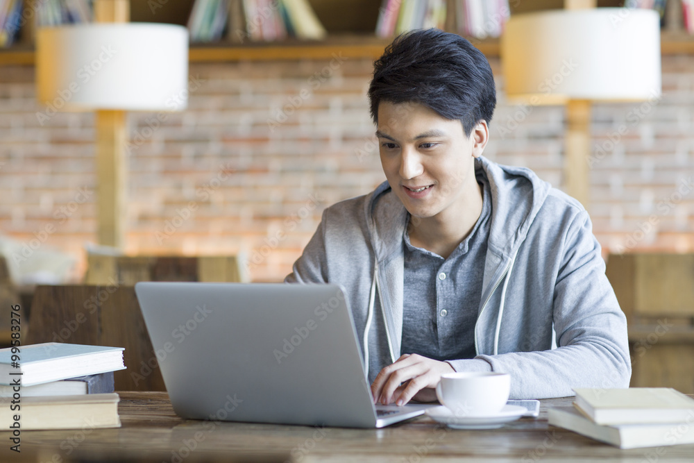 Young man using laptop in cafe Young man using laptop in cafe