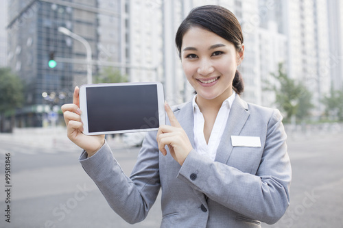 Confident businesswoman showing digital tablet