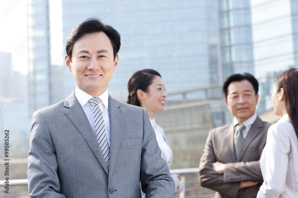 Confident businessman with partners in background Confident businessman with partners in background