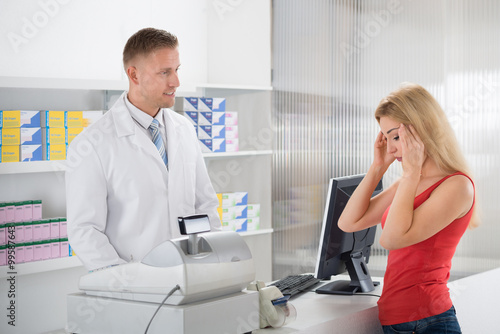 Pharmacist Looking At Customer Suffering From Headache