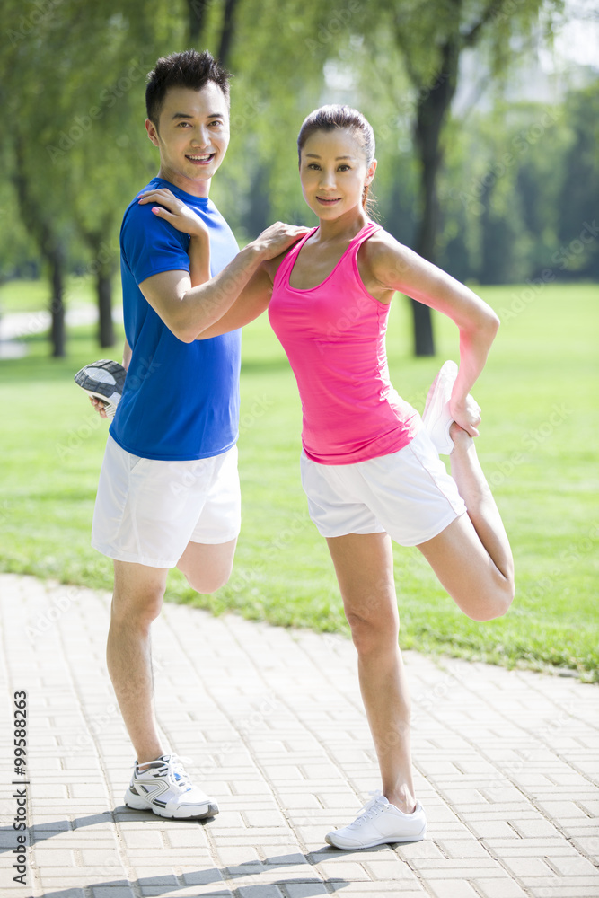 Portrait of young couple stretching in park