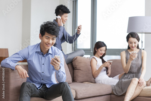 Young friends sitting on the sofa with smart phones 