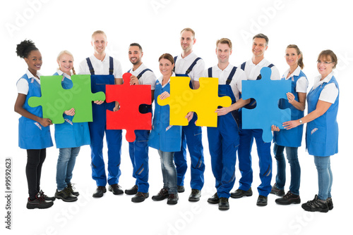 Confident Janitors Holding Jigsaw Pieces In Row