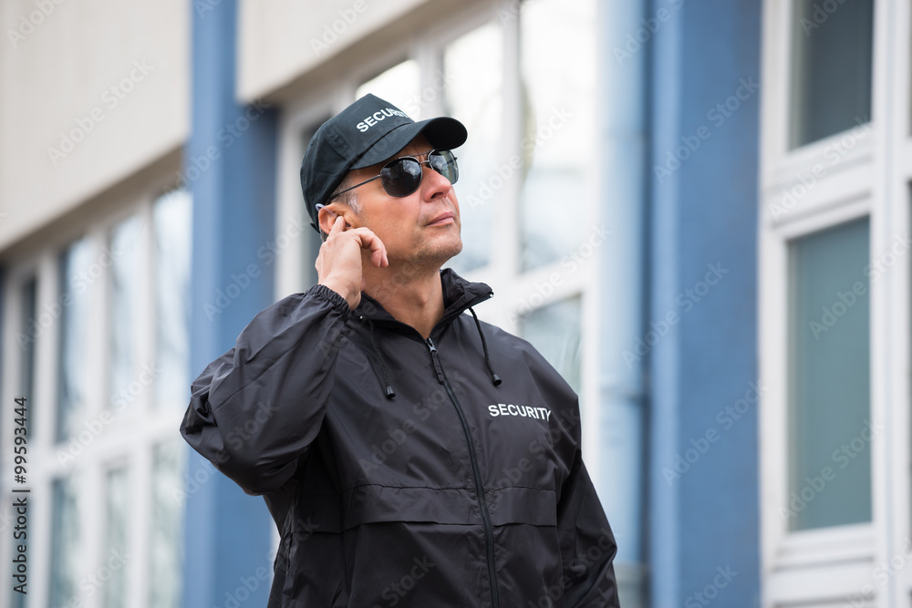 Security Guard Using Mobile Phone Outside Building