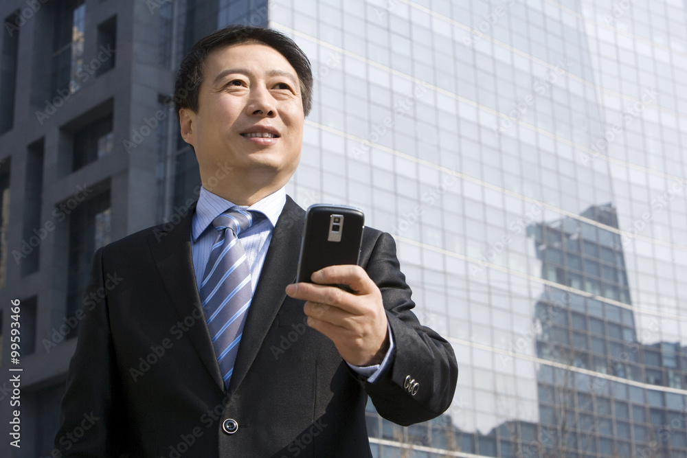 Older businessman text messaging on mobile device