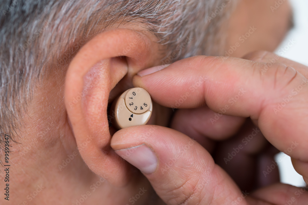 Fototapeta premium Closeup Of Businessman Inserting Hearing Aid In Ear