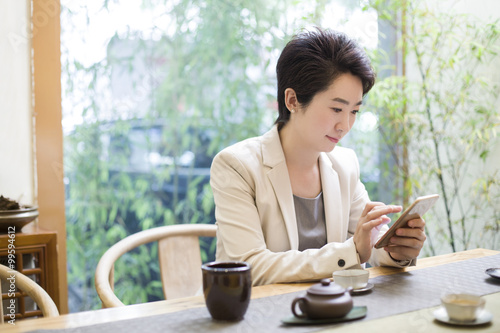 Businesswoman using smart phone in tea room